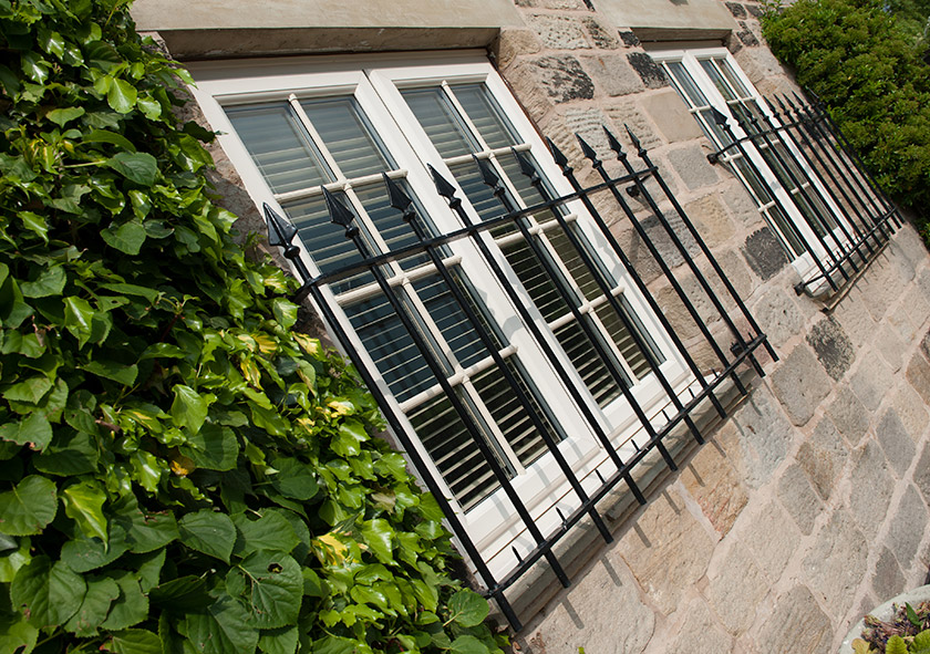 Replacement uPVC windows installed on a yellow brick building covered by black metal railing