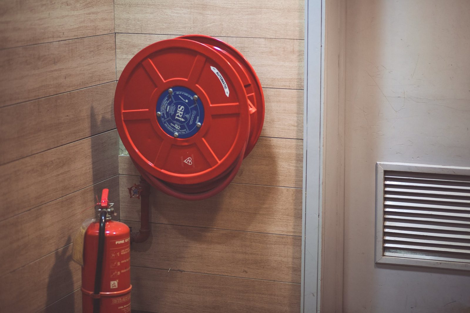 Fire extinguisher and fire hose by white door